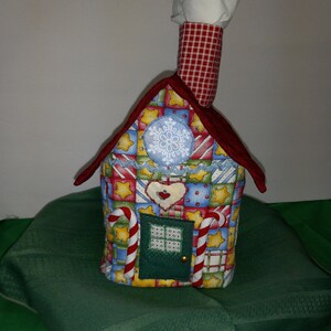 May include: A red and white checkered tissue box cover shaped like a gingerbread house with candy cane accents and a snowflake design.