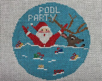 May include: A blue and white needlepoint ornament with a Santa Claus and reindeer falling into the water. The text "Cool Breeze" is written at the top of the ornament.