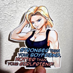 May include: A die-cut vinyl sticker featuring a blonde anime character with blue eyes wearing a black tank top. The text below the character reads, "STRONGER THAN YOUR BOYFRIEND, HOTTER THAN YOUR GIRLFRIEND!" in bold blue and pink lettering.