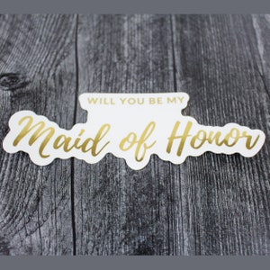 May include: White sticker with gold lettering that says "Will you be my Maid of Honor?"