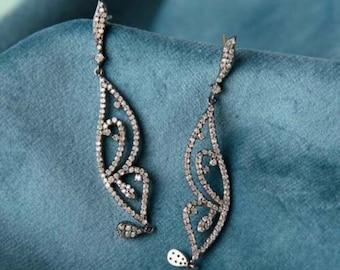 May include: A pair of silver dangle earrings with a butterfly design. The earrings are adorned with clear sparkling stones.