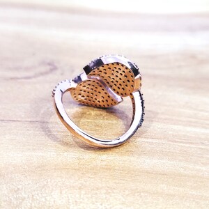 May include: A rose gold ring with two interlocking heart-shaped settings, each set with small sparkling stones.
