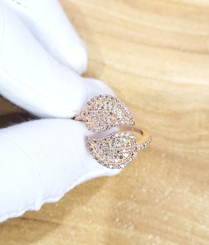 May include: A rose gold ring with two leaf-shaped bands set with sparkling diamonds.