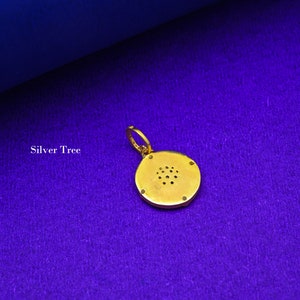 May include: A gold pendant with a round, textured design. The pendant has a small loop at the top for attaching to a chain.