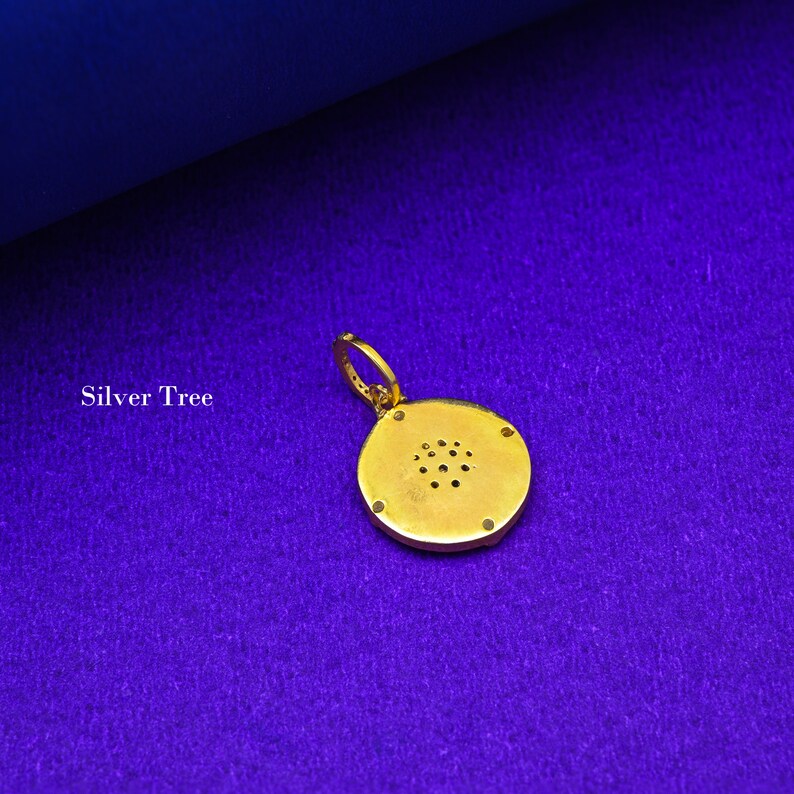 May include: A gold pendant with a round, textured design. The pendant has a small loop at the top for attaching to a chain.
