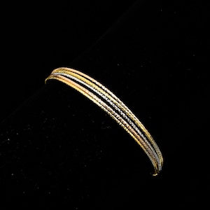 Könnte beinhalten: Ein filigranes Armband mit mehreren Strängen in Gold-, Silber- und Roségoldtönen. Das Armband ist vor einem schwarzen Hintergrund platziert, der das filigrane Design und die Farbvariationen des Schmucks hervorhebt. Geeignet für den Alltag oder besondere Anlässe.