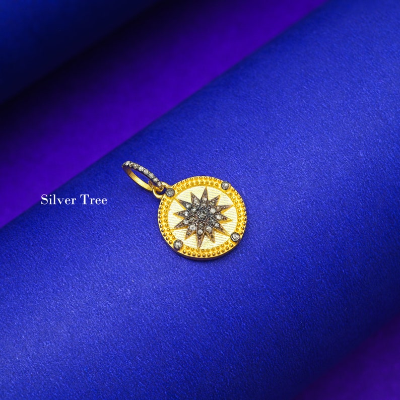 May include: A gold pendant with a starburst design set with black diamonds. The pendant is on a blue background.