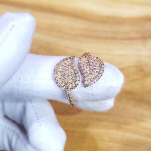 May include: A gold ring with two leaf-shaped designs set with clear stones.