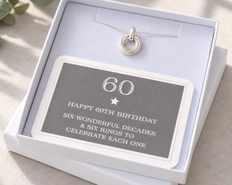 Può includere: Una collana in argento con un ciondolo composto da sei anelli intrecciati, presentata in una scatola regalo bianca. Un cartoncino all'interno riporta la scritta: 60, HAPPY 60TH BIRTHDAY, SIX WONDERFUL DECADES & SIX RINGS TO CELEBRATE EACH ONE.