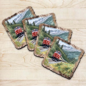 May include: Set of four coasters featuring a red train traveling through a mountain landscape. The coasters are made of wood and have a rustic, natural look.