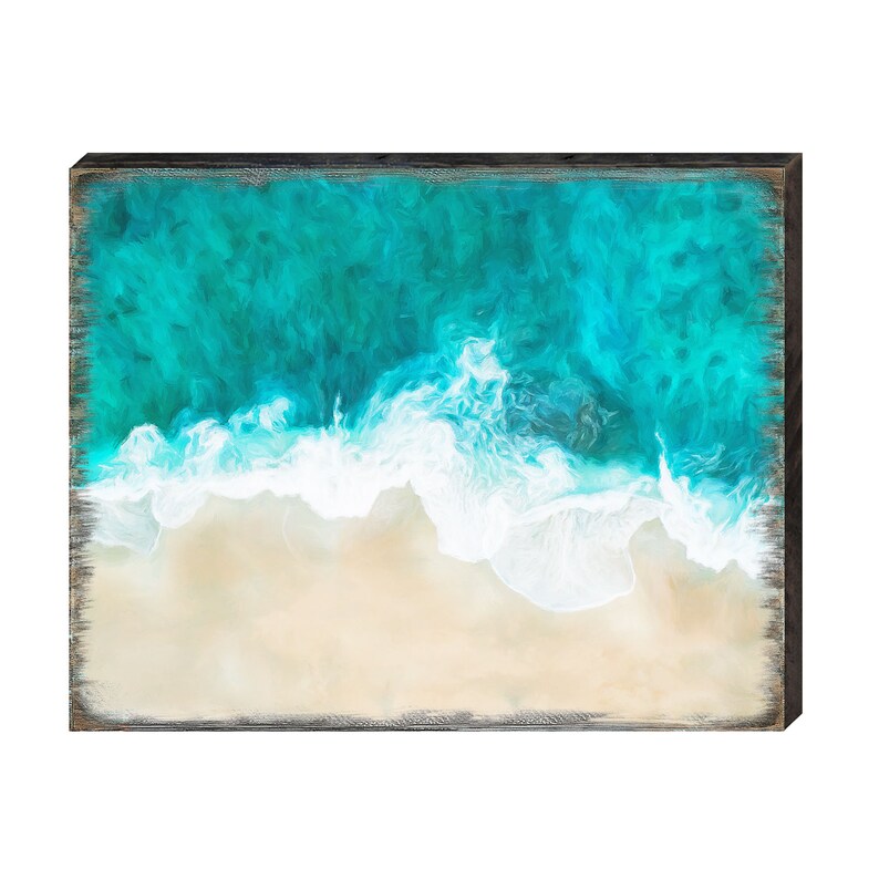 Puede incluir: Una pieza de arte mural rectangular de madera que representa una vista a&eacute;rea de una playa. La obra presenta agua de mar turquesa, olas blancas y una playa de arena. El marco es de color marr&oacute;n oscuro.
