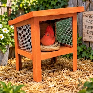 May include: A small orange wooden chicken coop structure with a slanted roof and wire mesh sides. Inside, a bright orange bird figurine sits in a straw nest. A wooden sign hanging nearby features the text Fresh Eggs Happy Days with a heart symbol.
