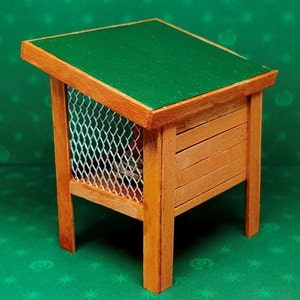 May include: A small wooden pet house with a green felt roof and a wire mesh front. The house is on a green background.