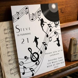 May include: A white invitation card with musical notes, silhouettes of dancers, and a vinyl record design. The text reads "Steve is turning 21" and includes party details. The card is placed on a vintage piano.