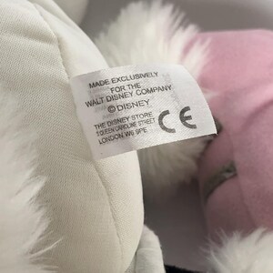 May include: White and pink plush toy with a white fur trim. The toy has a tag that reads "Made Exclusively for the Walt Disney Company &copy;Disney The Disney Store 3 Queen Caroline Street London W6 9PE CE".