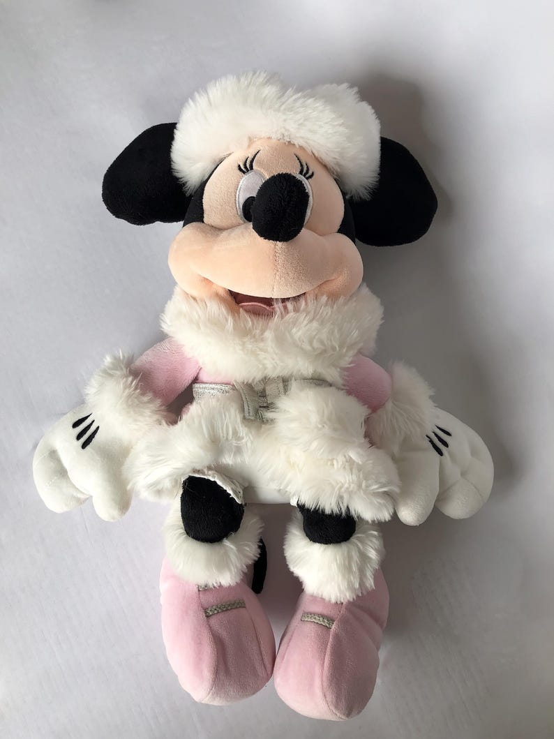 May include: A plush toy of Minnie Mouse wearing a white winter coat and hat with pink boots.