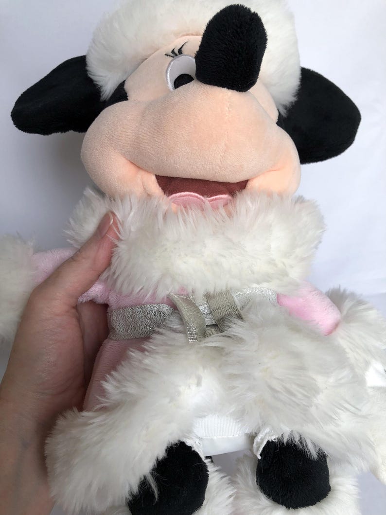 May include: A plush toy of Minnie Mouse wearing a pink and white winter coat with a silver trim. She has a black nose and large black eyes.