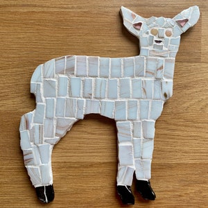Op de afbeelding: Een wit mozaïek hertenbeeld met zwarte hoeven. Het hert is gemaakt van kleine, witte tegels met een lichte glans.