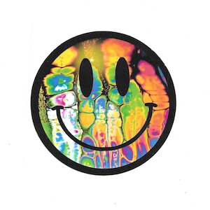 May include: A tie-dye smiley face sticker with a black outline. The smiley face is filled with a psychedelic pattern of swirling colors, including yellow, orange, green, blue, and purple.