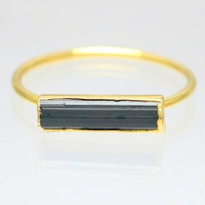 以下が含まれることがあります： 黒と白のバー型の宝石が付いた金の指輪