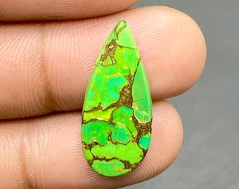 May include: A teardrop-shaped green turquoise cabochon with gold pyrite inclusions. The stone has a mottled green and gold pattern.