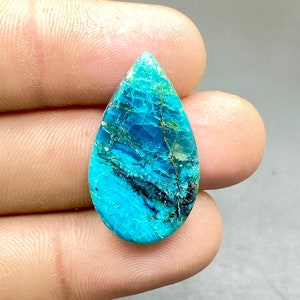 Op de afbeelding: Een traanvormige turquoise cabochon edelsteen met een blauw en groen kleurpatroon. De steen heeft een glad, gepolijst oppervlak en is gezet in een zilveren zetting.