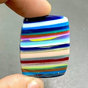 May include: A colorful, striped, glass cabochon with a variety of colors, including blue, green, red, yellow, and white.