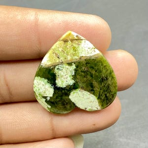 Op de afbeelding: Groen en wit hartvormig cabochon met een gemarmerd patroon. De steen heeft een gepolijste afwerking.