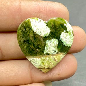 Op de afbeelding: Groen en wit hartvormig cabochon met een gemarmerd patroon.