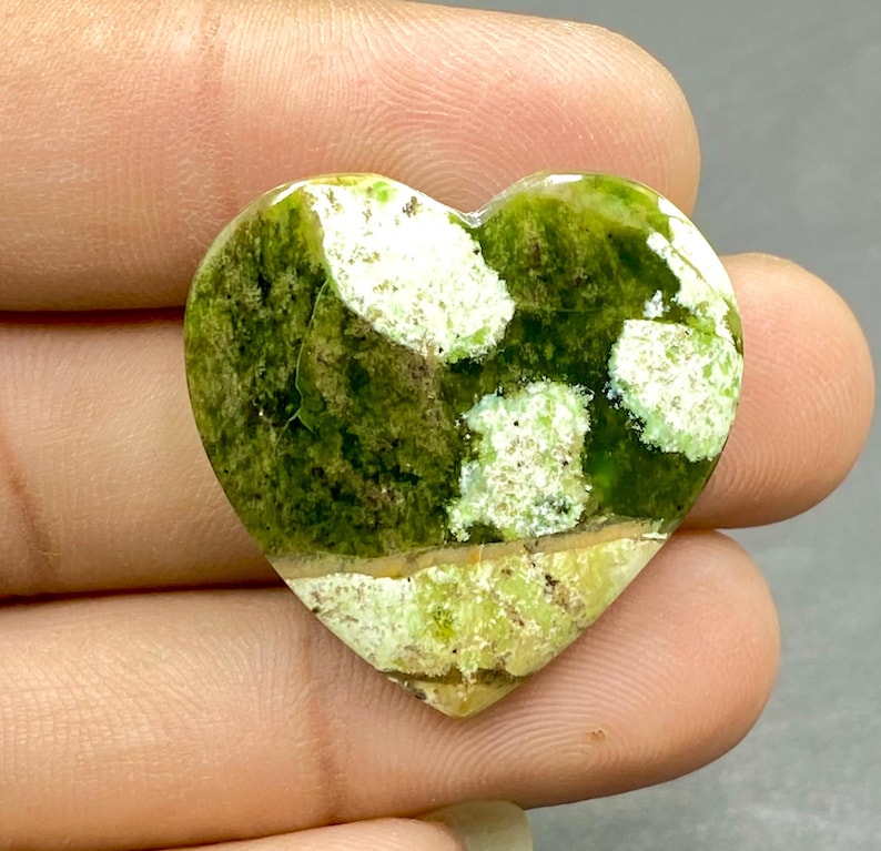 Op de afbeelding: Groen en wit hartvormig cabochon met een gemarmerd patroon.