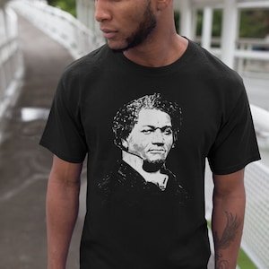 May include: Black t-shirt with a white graphic print of a man's face.