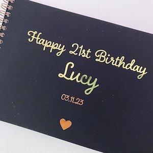 May include: Black spiral bound journal with gold foil lettering that says "Happy 21st Birthday Lucy 03.11.23" and a gold heart.