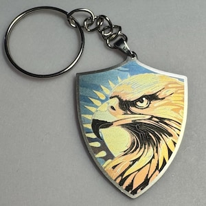 May include: A silver keychain with a shield-shaped charm featuring a colorful eagle head design.