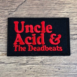May include: Black embroidered patch with red lettering that reads "Uncle Acid & The Deadbeats".