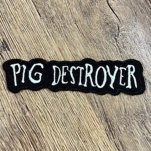 Könnte beinhalten: Schwarzer gestickter Aufnäher mit weißer Aufschrift "PIG DESTROYER".
