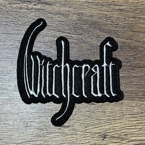 Puede incluir: Parche bordado en blanco y negro con la palabra "Witchcraft" en una fuente estilizada.