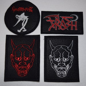 May include: Four black embroidered patches with red and white designs. One circular patch features the word "GHOSTMANE" and a skeletal figure. Another rectangular patch says "TRASH" in red. Two rectangular patches display a horned demon face.