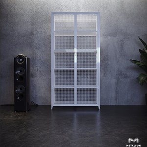 Può includere: Un armadio industriale in metallo bianco con un design a rete metallica e due ante. L'armadio ha sei ripiani ed è posizionato su un pavimento nero di fronte a un muro di cemento.