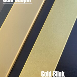 May include: Two gold-colored rectangular objects, labeled "Gold Jasper" and "Gold Blink", are displayed against a dark background. The "Gold Jasper" object has a smooth, matte finish, while the "Gold Blink" object has a textured, glittery appearance.