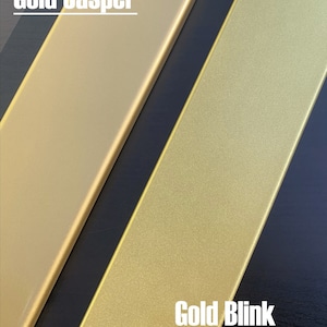 Może przedstawiać: Dwie pr&oacute;bki farby złotej, jedna oznaczona jako "Gold Jasper", a druga jako "Gold Blink". Pr&oacute;bki farby znajdują się na czarnym tle.