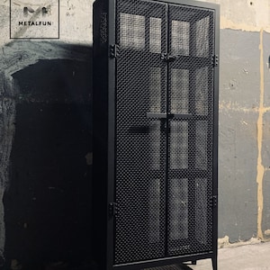 May include: Black metal cabinet with two doors and a wire mesh design. The cabinet has a simple, industrial style.