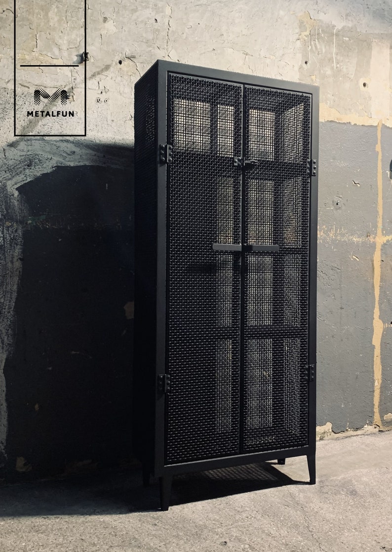 May include: Black metal cabinet with two doors and a wire mesh design. The cabinet has a simple, industrial style.