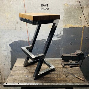 May include: A modern bar stool with a light wood seat and a black metal frame. The frame has a unique Z-shaped design. The logo "METALFUN" is visible in the upper left corner.
