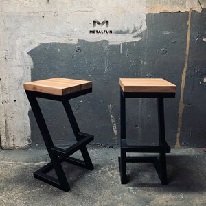 May include: Two modern bar stools with a light wood seat and black metal frame. The stools have a minimalist design, one with a Z-shaped leg and the other with a square leg. The logo "METALFUN" is visible in the upper left corner.