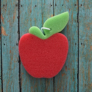 May include: Red sponge apple with a green stem and leaf. The apple is on a blue and brown wooden background.