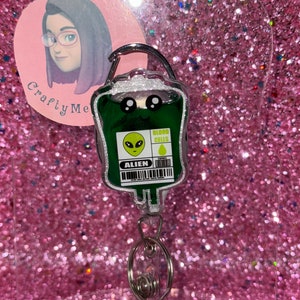May include: Green alien blood bag keychain with a silver retractable badge reel. The bag has a cartoon face with googly eyes and the text "Blood Cells" and "Alien".