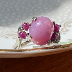 May include: A silver ring with a large pink gemstone surrounded by smaller pink gemstones.