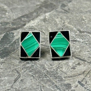 May include: A pair of square-shaped earrings with a green malachite stone set in a black and silver frame.