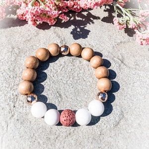 May include: A brown wooden beaded bracelet with white and red beads, and gold accents.