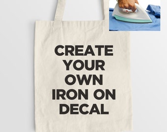 May include: A white canvas tote bag with black text that reads "CREATE YOUR OWN IRON ON DECAL".